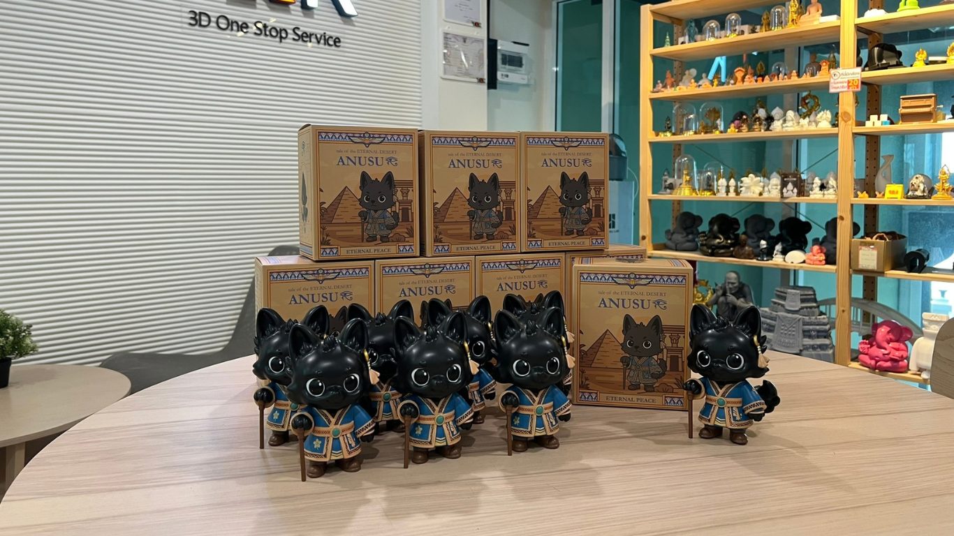 Art Toy แมวดำในชุดธีมอียิปต์ถือไม้เท้า วางคู่กล่องบรรจุลายพีระมิดก่อนส่งมอบให้ลูกค้า