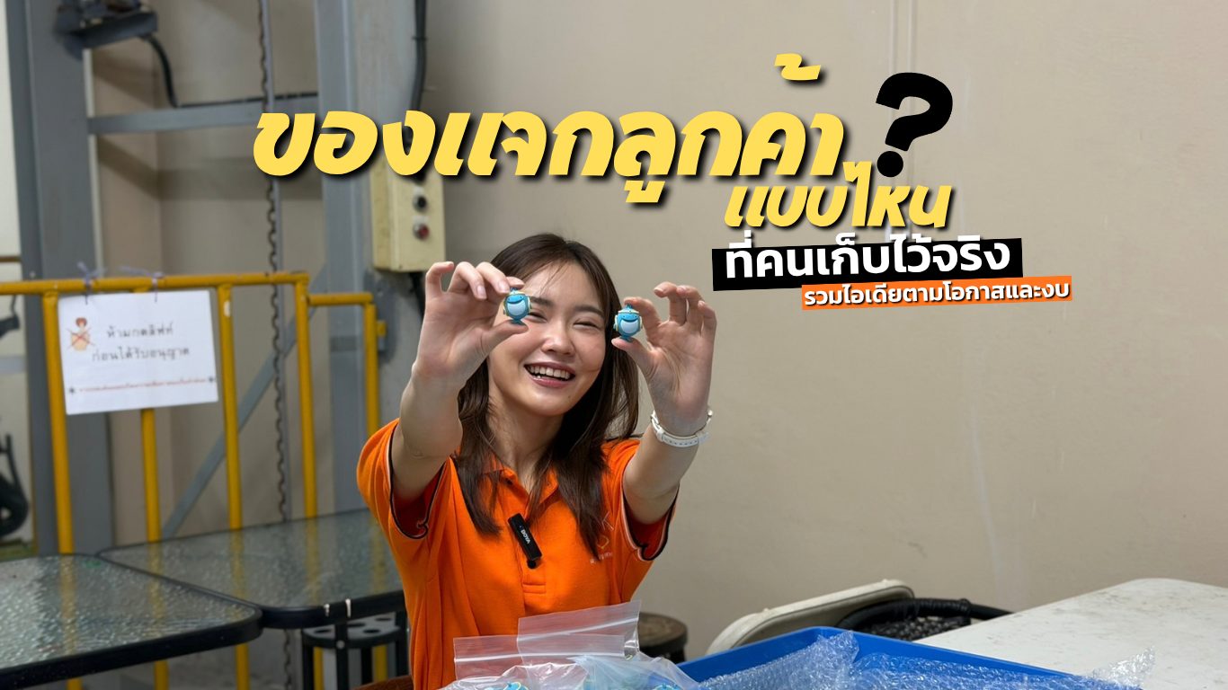 ผู้หญิงเสื้อส้มถือพวงกุญแจมาสคอตสีฟ้า 2 ชิ้น ภาพปกบทความของแจกลูกค้าแบบที่คนเก็บไว้จริง